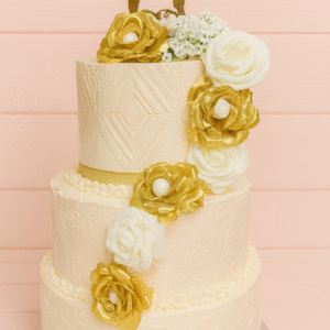 Gâteau de mariage à trois étages décoré de fleurs dorées et blanches – BGS Pâtisserie Nantes