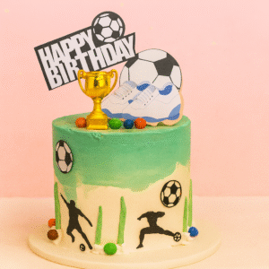 Gâteau d’anniversaire thème football avec ballon, coupe dorée, crampons et silhouettes de joueurs — BGS Pâtisserie.