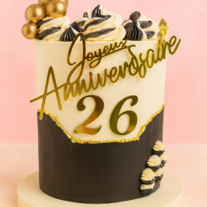 Gâteau d’anniversaire noir et or avec feuille d’or, boules dorées, crème bicolore et âge 26 en façade.