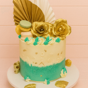 Gâteau ivoire et vert émeraude avec skyline orientale en relief, croissant de lune, éventails dorés, fleurs dorées et macarons.