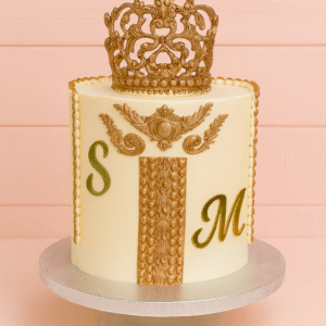Gâteau élégant ivoire & or avec couronne baroque, frise perlée et initiales personnalisées. Idéal fiançailles, mariage civil, baptême. 12+ saveurs, création sur-mesure.